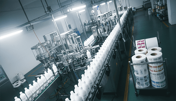 An assembly line with identical bottles being filled and labeled for different brand names.