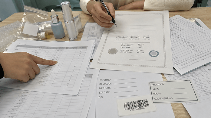 compliance certificates and spec sheets spread on factory office desk, iPhone-angle snapshot