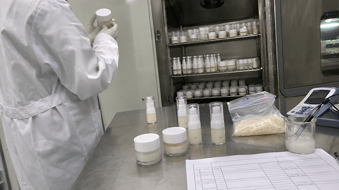 Laboratory bench with stability test samples in sealed containers, temperature chamber visible in background