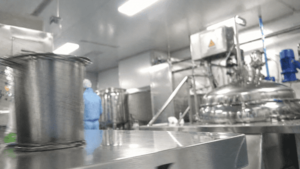 A split image showing a lab beaker on one side and a large manufacturing vat on the other.