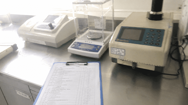 A checklist on a clipboard next to cosmetic lab equipment
