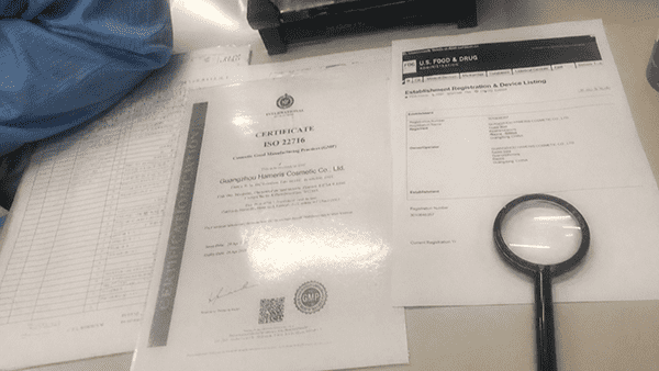 A magnifying glass hovering over an ISO 22716 certificate
