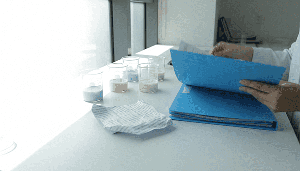 Testing and supplier verification before sampling A beauty founder comparing product samples, a target-market checklist, packaging notes, and supplier document files before choosing a manufacturer.