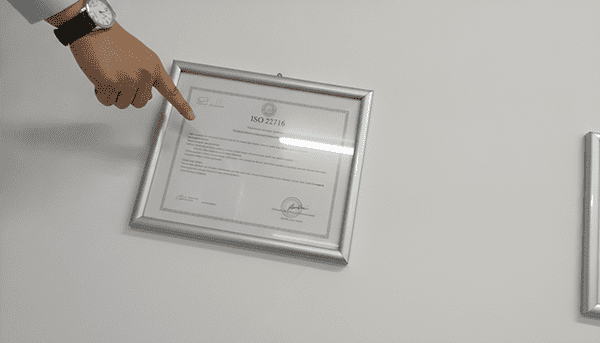 Four Pillars of Cosmetic Supplier Verification A magnifying glass hovering over a cosmetic cream jar, a sample vial, a factory icon, and a certificate document, symbolizing the four key verification areas.