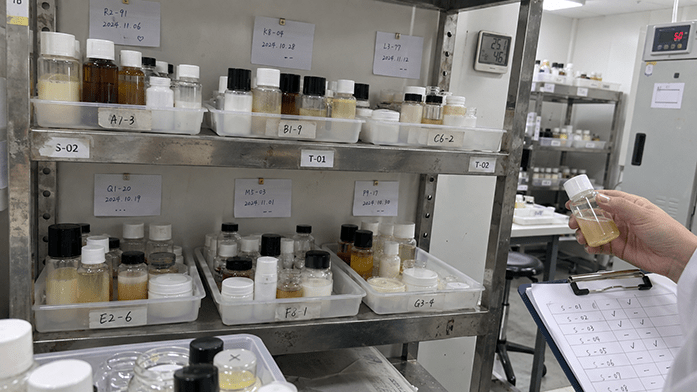 sample trays of serum and cream lots lined up on a stability shelf under a label with trial dates, iPhone-angle snapshot